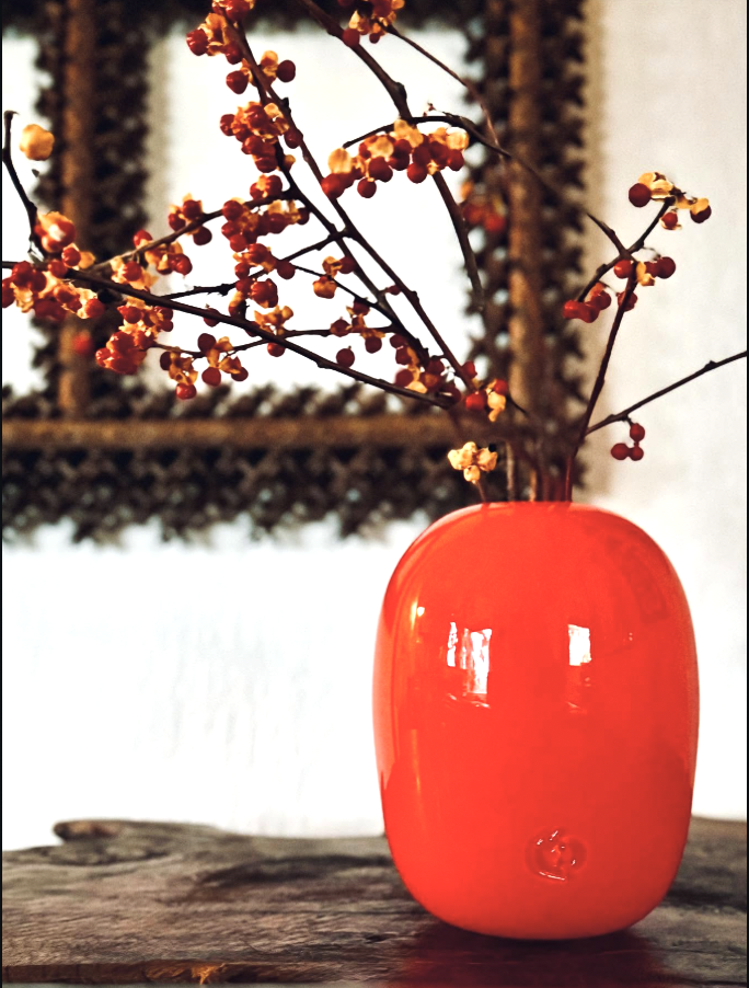 red vase with berry plant mirror in background